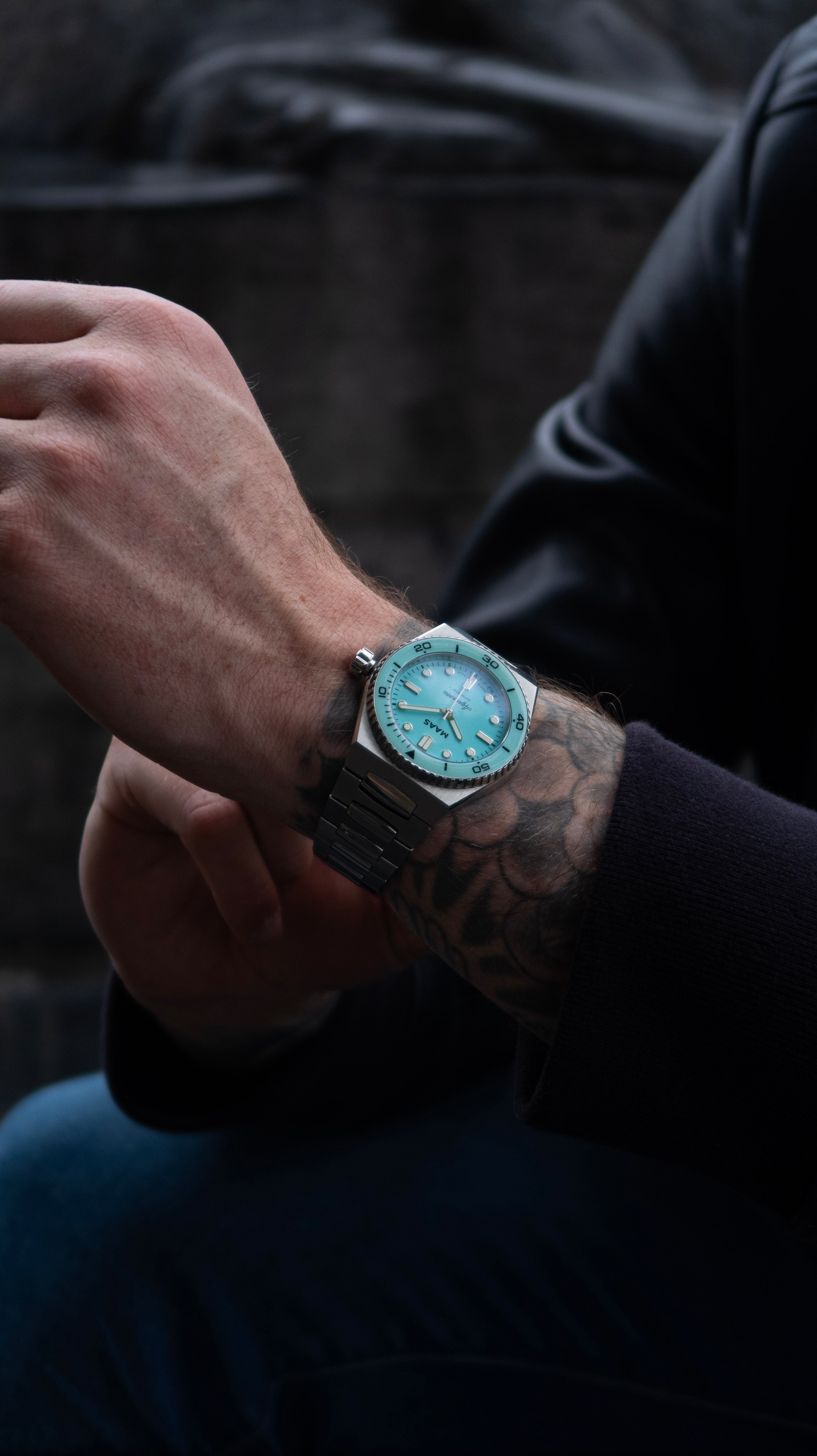 Person wearing a turquoise watch on a dark background