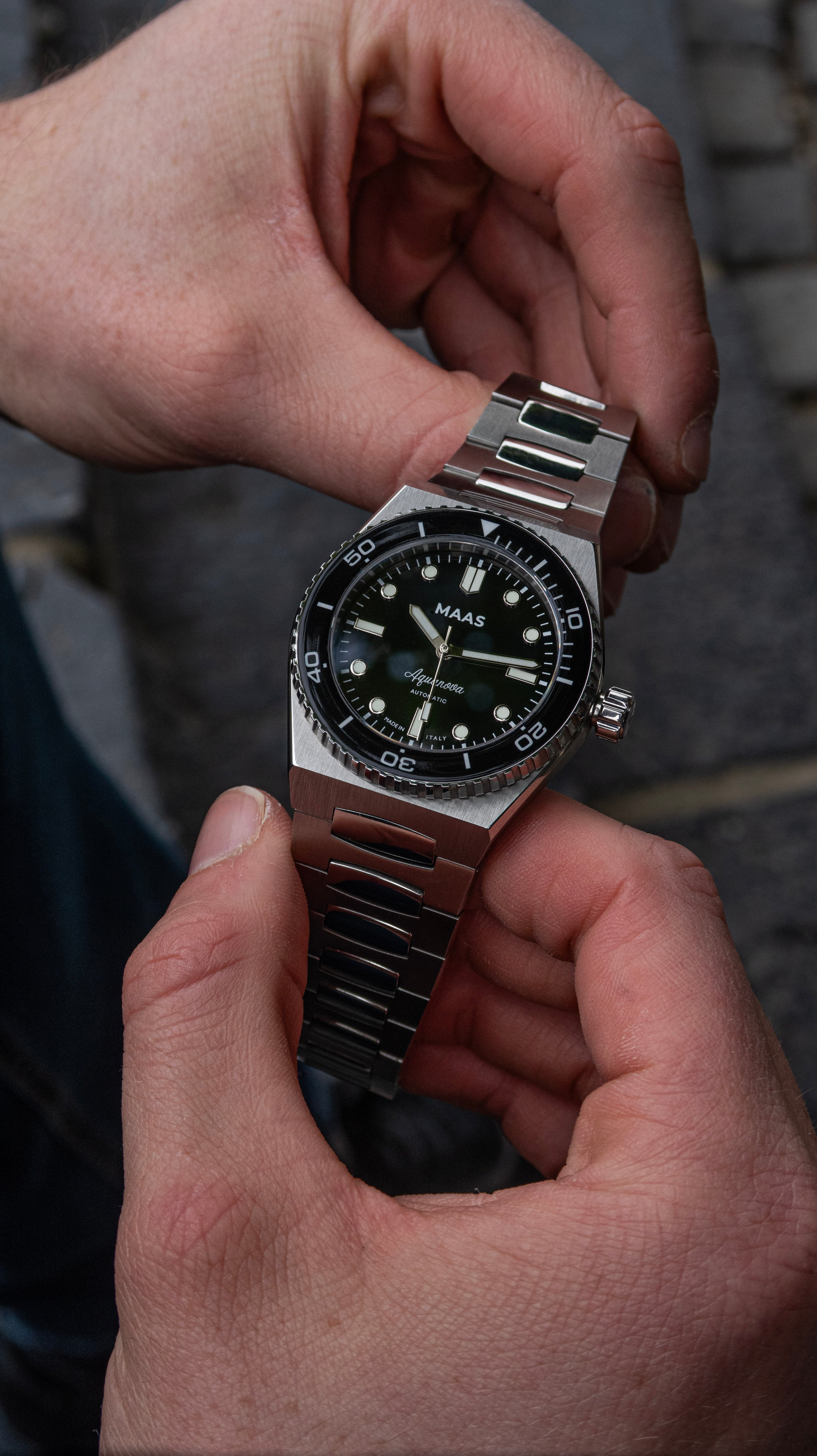 Person holding a black watch with a blurred background