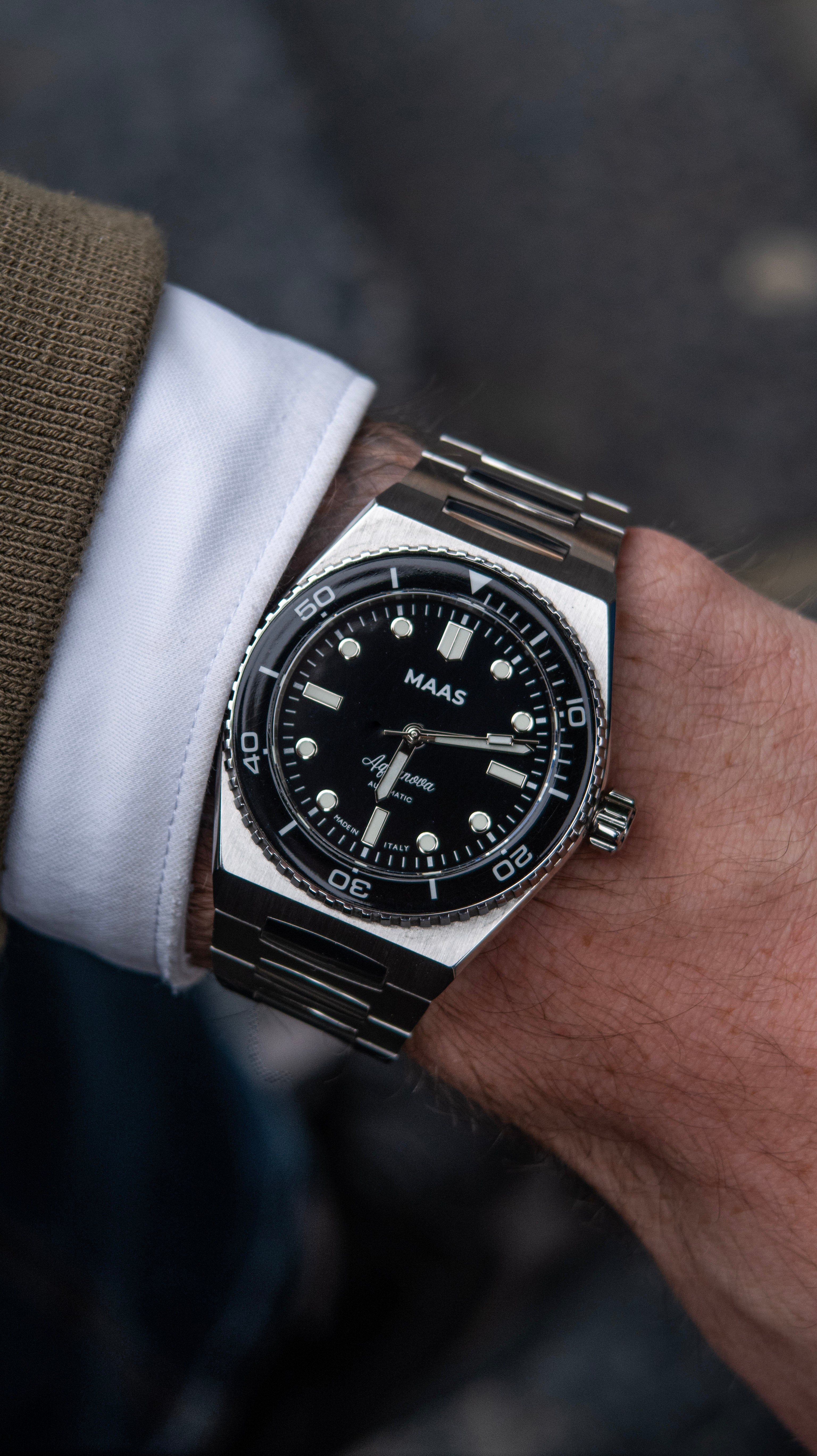 Close-up of a person wearing a wristwatch with a dark face and metallic band.
